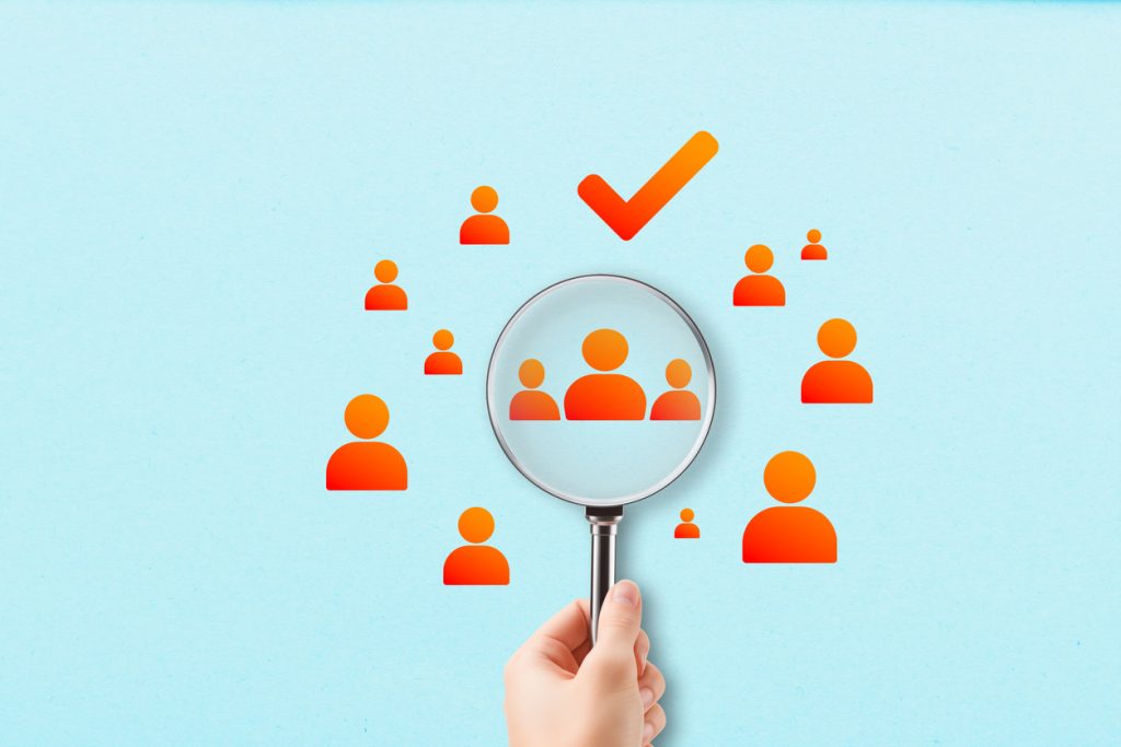 A concept of a hand magnifying icons of people shows the power of ai for networking when making business connections. 